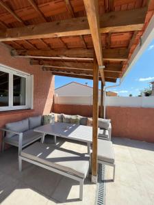 a patio with a table and chairs under a wooden roof at Villa piscine confort cosy in Brouilla