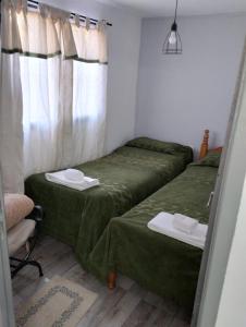 2 camas en una habitación pequeña con sábanas verdes en El RANCHO en San Martín