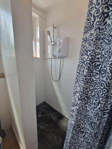 La salle de bains est pourvue d'une douche avec un rideau de douche bleu et blanc. dans l'établissement Direct Booking Prices, Studio Apartment, Free Parking, Wifi, Central, Quiet, à Exeter