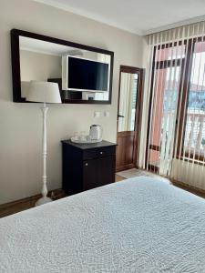 a bedroom with a bed and a mirror and a tv at Red House Family Hotel in Ravda