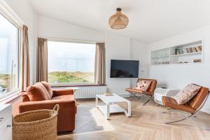a living room with two chairs and a tv at Zeezicht Villa Zee aan het strand in Bergen aan Zee