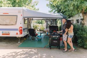 un hombre y una mujer parados frente a una caravana en Camping Sènia Caballo de Mar, en Pineda de Mar