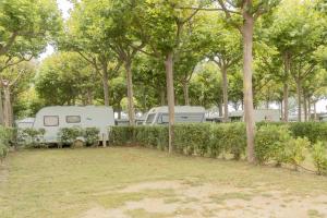 two rvs parked in a park with trees at Camping Sènia Caballo de Mar in Pineda de Mar