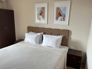 a bedroom with a bed with white sheets and pillows at Red House Family Hotel in Ravda