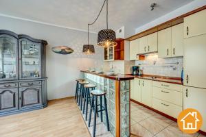 a kitchen with white cabinets and bar stools at Apartament na deptaku in Świnoujście