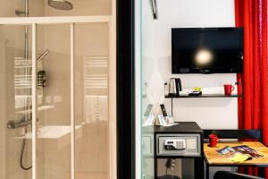 baño con ducha y TV en la pared en Hôtel Le Loft, en Trie sur Baise