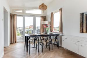 a dining room with a black table and chairs at Zeezicht Villa Zee aan het strand in Bergen aan Zee