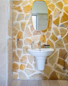 a bathroom with a stone wall with a sink and a mirror at The Life Suites in Limnionas