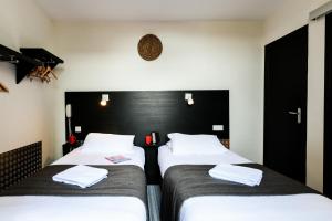 2 Betten in einem schwarz-weißen Zimmer in der Unterkunft Hôtel Le Loft in Trie sur Baise