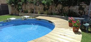 a pool on a wooden deck with a table and flowers at Hornillos Meeting Point (Pilgrim Hostel) in Hornillos del Camino
