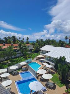 an aerial view of a resort with a pool and umbrellas at Vivenda dos Corais in Porto De Galinhas