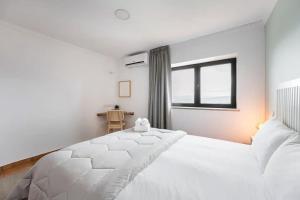 a white bedroom with a large white bed and a window at Casa Letrigo in Arcos de Valdevez +34 photos