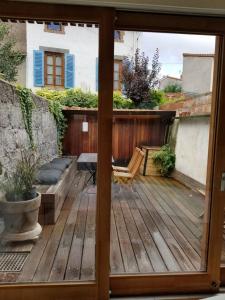 Une porte ouverte s'ouvre sur un patio doté d'une terrasse en bois. dans l'établissement Maison hypercentre calme, terrasse, garage, poêle, à Clermont-Ferrand