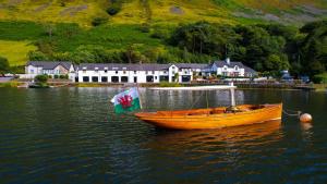 a wooden boat in the water with a house in the background at Tynycornel Hotel in Tal-y-llyn