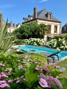 VILLA DU CEDRE Honfleur في أونفلور: بيت فيه مسبح في حديقة فيها ورد