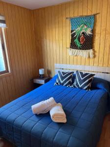 a blue bed with two towels on top of it at cabañas anvi pucon in Pucón