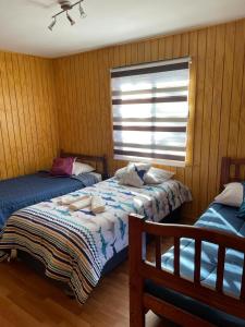 1 dormitorio con 2 camas y ventana en cabañas anvi pucon, en Pucón