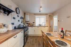 a kitchen with white cabinets and a wooden table at Broomfield Cottage Nr Pickering - DOGS STAY FOR FREE in Pickering
