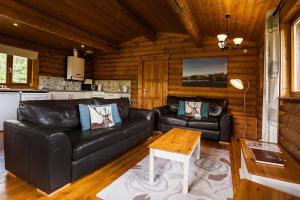 a living room with a black leather couch and a table at Bullfinch - 2 Bed Lodge in Saxtead