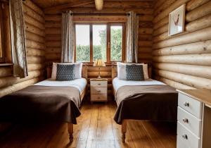 two beds in a log cabin with a window at Bullfinch - 2 Bed Lodge in Saxtead