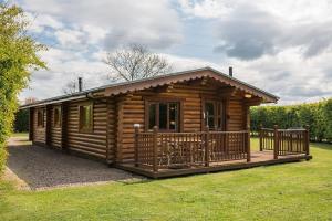 a log cabin with a deck on the grass at Bullfinch - 2 Bed Lodge in Saxtead
