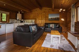 a living room with a leather couch and a table at Bullfinch - 2 Bed Lodge in Saxtead