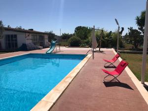a swimming pool with two chairs and a slide at Sans-souci in Nardò