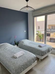 two beds in a bedroom with blue walls at Immense RoofTop Lyon 3 chambres, 4 places de parking in Lyon