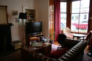 a living room with a leather couch and a television at Argyle Backpackers in Edinburgh