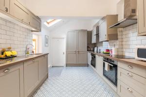 uma grande cozinha com armários brancos e piso em azulejo em Northumberland Boutique Guest House #1 em Coventry