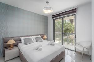 ein Schlafzimmer mit einem großen weißen Bett und einem Fenster in der Unterkunft Trust Inn garden in the city in Tel Aviv
