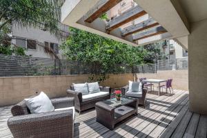 eine Terrasse mit Korbstühlen und einem Tisch in der Unterkunft Trust Inn garden in the city in Tel Aviv