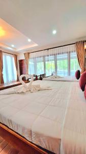 1 cama blanca grande en una habitación con ventanas en Amantra homestay & village en Surat Thani