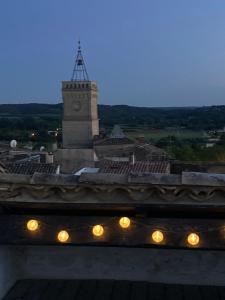 una torre de reloj en la parte superior de un edificio con luces en La Maison D'Aimé en Saint-Quentin-la-Poterie