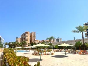 uma piscina com guarda-sóis e cadeiras e uma piscina em Apartamentos Deluxe Marina Dor em Oropesa del Mar