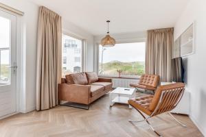 a living room with a couch and a chair at Zeezicht Villa Strand direct bij zee in Bergen aan Zee