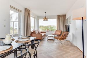 salon ze stołem, krzesłami i kanapą w obiekcie Zeezicht Villa Strand direct bij zee w mieście Bergen aan Zee