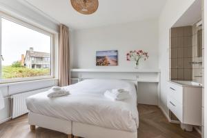 a white bedroom with a bed and a window at Zeezicht Villa Strand direct bij zee in Bergen aan Zee
