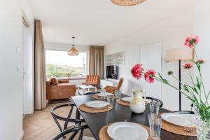 a dining room and living room with a table and chairs at Vernieuwd Zeezicht Villa Strand Luxe in Bergen aan Zee