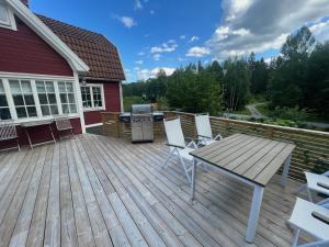 een terras met een tafel en stoelen en een grill bij Tutviksvägen 35 in Vendelsö