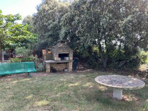 uma mesa de piquenique e um forno de pedra num quintal em Les oliviers du pradon em Lagarde-Paréol