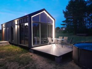 a black cabin with a deck and a table and chairs at Domki letniskowe Jastrzębna in Sztabin