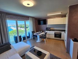 a living room with a white couch and a kitchen with a table at Apartments Riva-Interauto in Umag