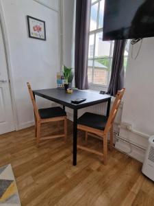 a black table and chairs in a room with a window at Studio Apartment, Private Parking, Walk To Centre, Uni and Hospital, Long Stay Prices in Exeter