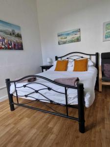 a bedroom with a bed with white sheets and orange pillows at Studio Apartment, Private Parking, Walk To Centre, Uni and Hospital, Long Stay Prices in Exeter
