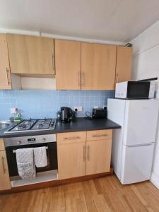 a kitchen with a stove and a white refrigerator at Studio Apartment, Private Parking, Walk To Centre, Uni and Hospital, Long Stay Prices in Exeter