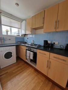 a kitchen with a stove and a washing machine at Studio Apartment, Private Parking, Walk To Centre, Uni and Hospital, Long Stay Prices in Exeter