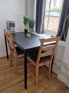 a black dining room table with two chairs and a window at Studio Apartment, Private Parking, Walk To Centre, Uni and Hospital, Long Stay Prices in Exeter