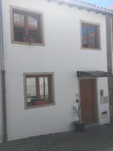 een wit gebouw met een bruine deur en ramen bij Casa do Castelo I in Bragança