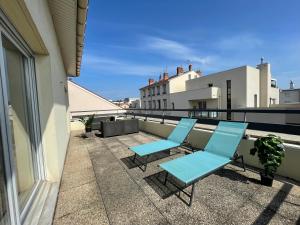 a patio with two blue chairs on a balcony at Immense RoofTop Lyon 3 chambres, 4 places de parking in Lyon